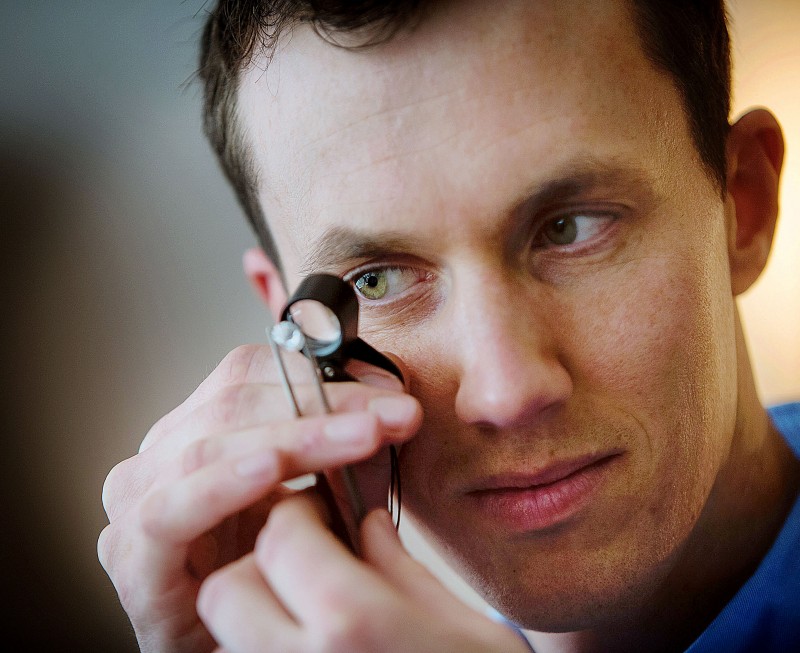 Engagement ring designer, diamond expert and handmade jeweller Julian Bartrom examining and brilliant cut diamond